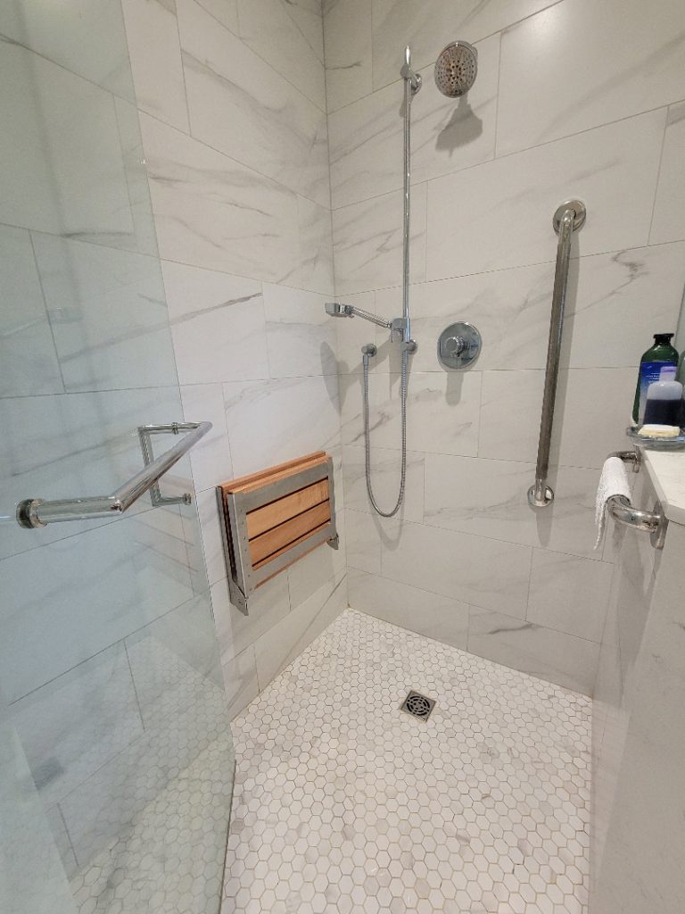 Bathroom with no-threshold shower. No-threshold shower with fold down seat, hand held shower head and grab bars.